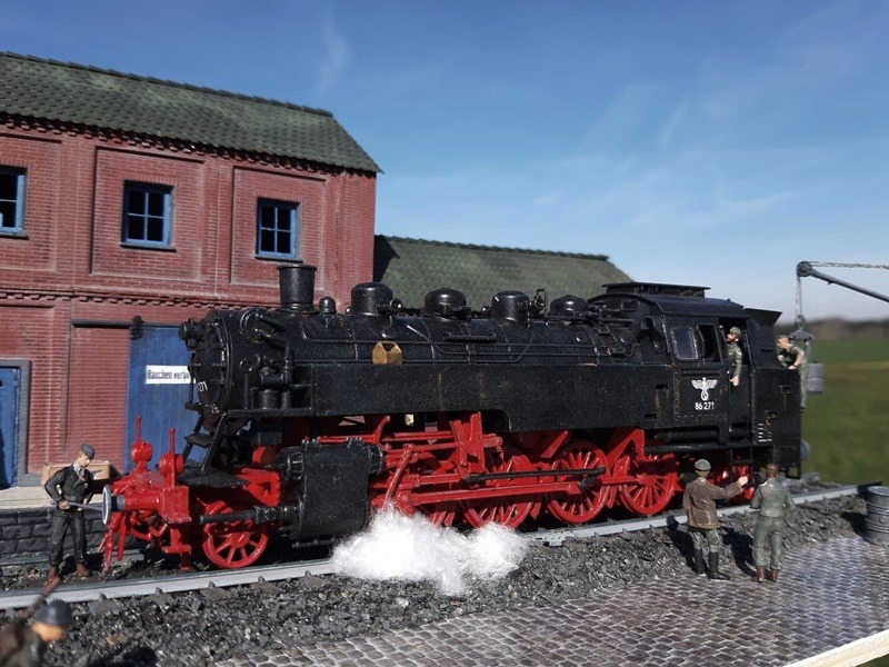 Eine Lokomotive der Baureihe 86 wird im Bahnhof für die nächste Fahrt wieder mit Kohle und Wasser befüllt